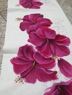 two white towels with pink flowers painted on them, sitting on the floor next to each other