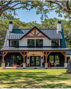 a large house with a metal roof in the middle of a grassy area surrounded by trees