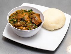 a white plate topped with a bowl of stew and mashed potatoes