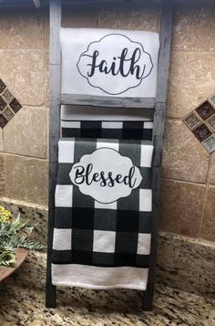 two black and white towels hanging on a towel rack in a kitchen with tile backsplash