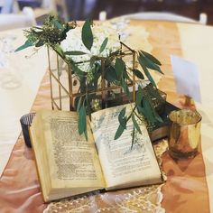 an open book sitting on top of a table next to a vase filled with flowers