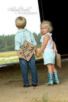 two young children holding hands and standing in front of a barn