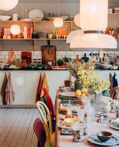 a dining room table with plates and bowls on it, next to shelves filled with dishes