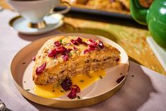 a piece of bread with cranberries and orange sauce on a plate next to a cup of coffee