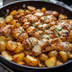 a skillet filled with chicken and potatoes covered in melted cheese on top of it