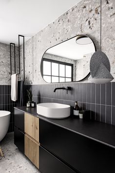 a black and white bathroom with a round mirror on the wall above the bathtub