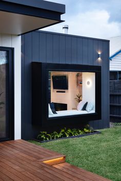 an outdoor living area with wooden decking and black cladding on the side of a house