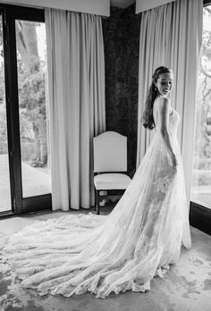 a woman standing in front of a window wearing a wedding dress