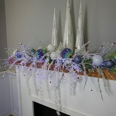 a fireplace mantel decorated with christmas decorations and silver candlesticks on top of it