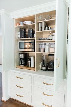 a kitchen with white cabinets and gold handles on the doors is filled with coffee machines