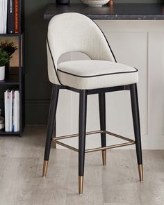 a white bar stool sitting on top of a wooden floor next to a book shelf