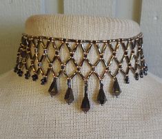 To bead this choker, I did netted weave using: bronze, bugle beads, brass and black, size 9 and 10, seed beads, and  faceted, bronze, glass drop beads.   Because I added an extender, the length is adjustable; starting at 31 cm. (12 1/4"), up to 48.5 cm. (19").  It closes with a black, lobster claw clasp. If you would prefer the tail loop up rather than dangle, just let me know at time of purchase, and I can easily add a hook. at at the end. The last photo shows more of my work.   If you don't see the listing in my shop, contact me and, chances are, if I don't have it in stock I can probably make a custom necklace for you. This is a simple version of the amazing collars made by Native-Americans, for centuries, up to the present.  To see some examples, go to the National Museum of the Americ Beading Netting, Elegant Evening Wear, Fairy Garden Diy, Black Seed, Bugle Beads, Beaded Choker Necklace, Drop Beads, Bright Gold, Faceted Glass