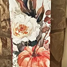 a painting of flowers and pumpkins is hanging on the wall in front of a brick wall