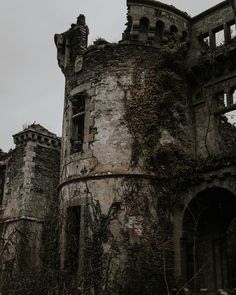 an old castle with ivy growing on it's walls and the sky in the background