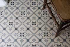 a wooden stool sitting on top of a tiled floor next to a sink and toilet