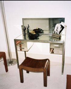 a glass desk with a mirror on top and a chair in the middle next to it