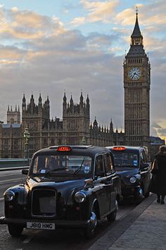 two taxi cabs parked next to each other in front of the big ben clock tower