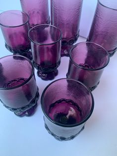 purple glasses are arranged in a circle on a white surface