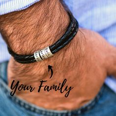 a man wearing a black leather bracelet that says your family