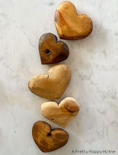 five wooden hearts arranged in a row on a marble surface