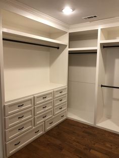 an empty walk in closet with white cabinets and drawers