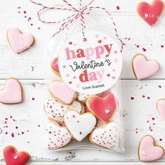 valentine's day cookies in a bag on a white table with pink and red hearts