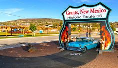 an old car is parked in front of the entrance to a historic route 66 sign