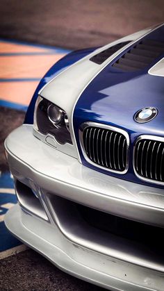 the front end of a blue and white bmw sports car on a race track with it's hood up