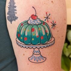 a woman with a cake tattoo on her left arm and shoulder, in front of a christmas tree