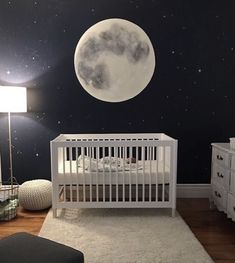 a baby's room with a white crib and stars in the sky on the wall