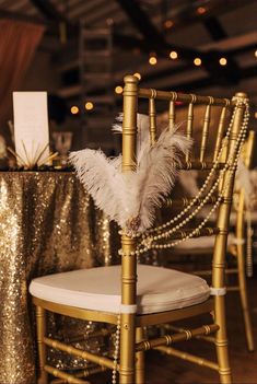 a chair with a white feather on it next to a gold table cloth and chairs