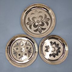 three metal plates with flower designs on them