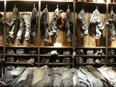 many pairs of jeans are hanging on the wall next to each other in an old fashion store