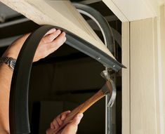 a person is working on a window frame with a wrench in their left hand