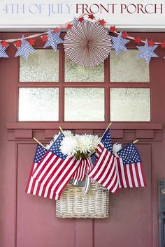 an american flag decoration hanging on the front door with flowers in a wicker basket