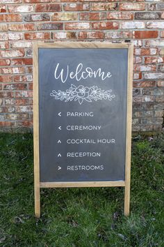 a chalkboard sign in front of a brick wall with the words welcome written on it