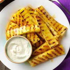 grilled pineapples on a white plate with ranch dip in a small bowl