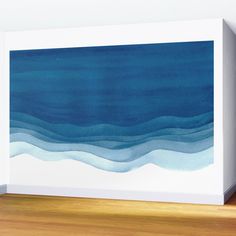 an abstract painting with blue and white watercolors on the wall next to a wooden floor