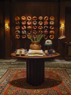 a table topped with donuts and flowers on top of a rug next to a wall