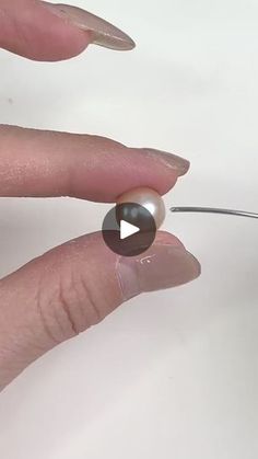 a person is holding a small object in their left hand and the other hand has a needle through it