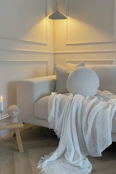 a living room with a white couch and two candles on the table next to it