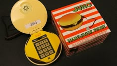 a yellow phone sitting on top of a table next to a box with a hamburger phone