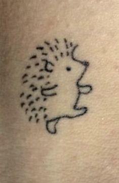 a small hedgehog tattoo on the back of a woman's shoulder