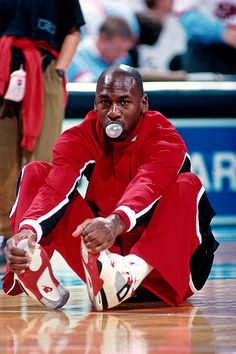 a man sitting on the ground with his foot in front of him, wearing red and white