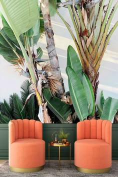 two orange chairs sitting next to each other in front of a palm tree wall mural