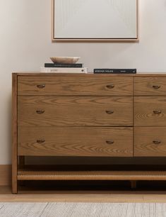 a wooden dresser sitting in front of a painting on the wall next to a rug