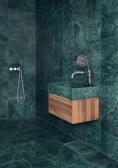 a bathroom with green marble walls and flooring, including a wooden sink countertop