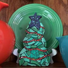 a ceramic christmas tree sitting on top of a table next to plates and vases