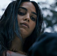 a close up of a person with dark hair and black eyeliners, looking off to the side