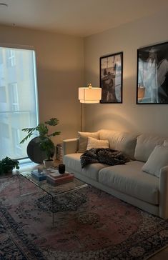 a living room filled with furniture next to a large window and a painting on the wall